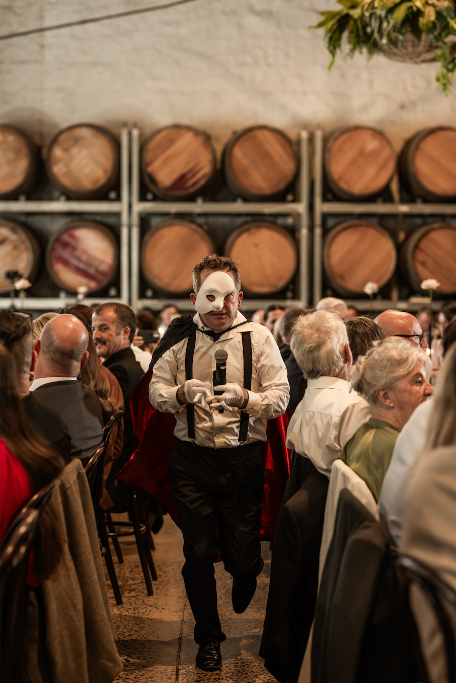 Jon Bode in costume moving between tables among guests in a winery barrel room